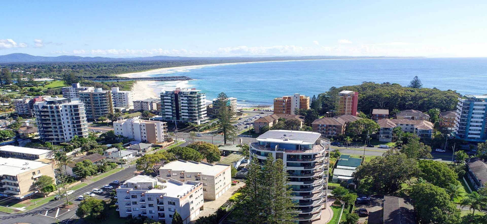 Un quartier résidentiel comprenant plusieurs immeubles d’appartements, des rues et, au loin, une plage.