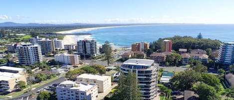 A residential area with multiple apartment buildings, roads, and a beach in the background.