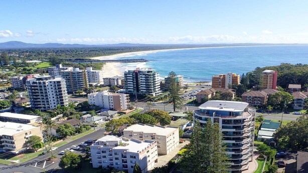A residential area with multiple apartment buildings, roads, and a beach in the background. - Twin Pines 301 - CBD Location (Forster)