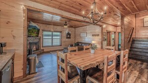 L’intérieur d’un chalet en bois comprend une table à manger, des chaises, une cheminée et un escalier.