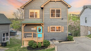 Une maison à deux étages avec un porche, une pancarte de bienvenue et une petite terrasse.