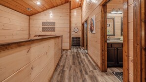 Un intérieur en bois avec un comptoir d’accueil, un couloir menant à la cuisine et un tableau encadré au mur.