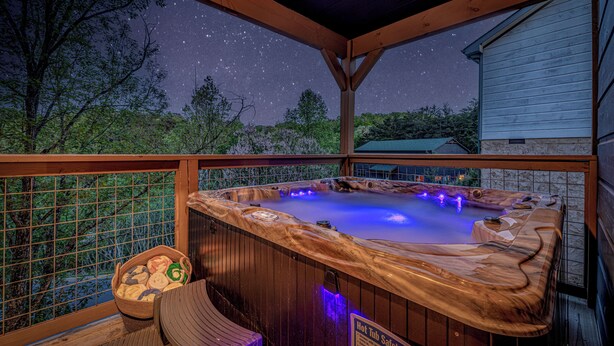 Un bain à remous avec un revêtement extérieur en bois et une vue imprenable sur le ciel étoilé.