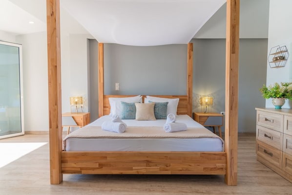 A wooden four-poster bed with white bedding, two bedside tables with lamps, and a wooden dresser.