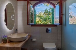 A bathroom with a round sink, a toilet, and a window with green shutters. - Amor Beach Villa 3 Bedrooms with huge pool, BBQ, near the beach. (Zakynthos)