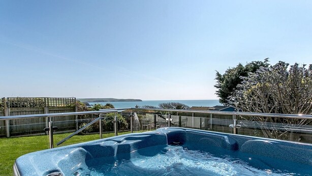 A hot tub with a clear view of the sea and a grassy area in the foreground. - Luxury property Sleeps 8 - Sea views & hot tub - 200m from beach! (Bigbury-on-Sea)