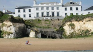 A coastal building with multiple windows and a staircase leading up to a cliff. - 1h from central London and 30min from Dover, opposite stairs to sandy beach (Broadstairs)