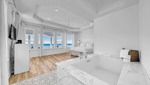 Een moderne slaapkamer met een groot raam, een marmeren badkuip en een houten vloer.