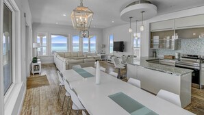Een moderne keuken met een groot eiland, witte kasten en uitzicht op de oceaan.
