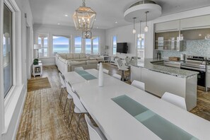 Una cocina moderna con una isla grande, armarios blancos y vistas al océano.