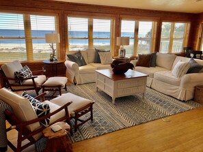 A spacious living room with a large window overlooking a beach, furnished with a white sofa, chairs, and a coffee table. - "Shifting Sands" Private Beach Front 3 Bd, 2 Bath, sleeps 8  (Alligator Point)
