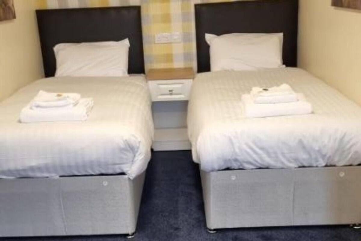 A hotel room with two beds, a checkered wall pattern, and a dark carpet.
