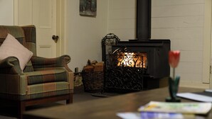 A cozy living room with a plaid sofa, a fireplace, and a coffee table with papers. - Cottage Sleeps 13 - Stunning Views! (Berambing)