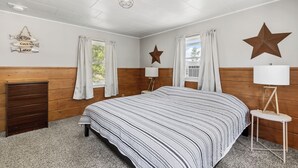 A bedroom with a large bed, wooden walls, a star decoration, and a 'Gone Fishin' sign.