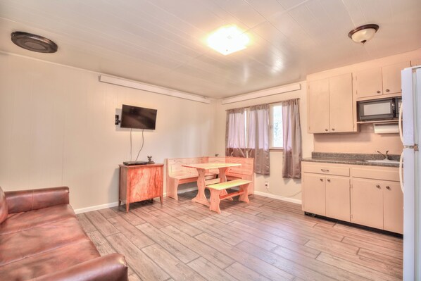 Cozy living space with a kitchenette, dining area, and seating area featuring a flat-screen TV and leather sofa.