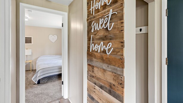 Un pasillo con pared de madera y un cartel que dice 'Hogar, dulce hogar'.