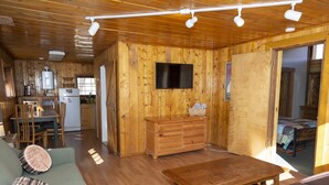 A wooden cabin interior with a living room, dining area, and kitchen. - The Peggy! (Creede)