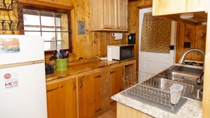 A wooden kitchen with a refrigerator, microwave, and sink. - The Peggy! (Creede)