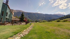 A building with a green facade, a stone pathway, and a mountainous backdrop. - Fp209 Fox Pine Inn 1 Bedroom Condo by RedAwning (Copper Mountain)