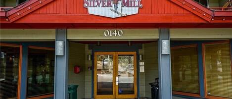 The entrance to Silver Mill with a red awning, double doors, and a wheelchair-accessible ramp.