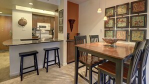 A modern kitchen with a central island, bar stools, and a dining table with chairs.