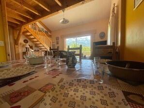 A dining area with a wooden staircase, a table set with plates, glasses, and a pitcher, and a view of mountains through a window. - Quiet house with terrace in Saint-Pons (Saint-Pons)