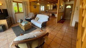 A spacious living area with a sofa, a television, and a dining table.