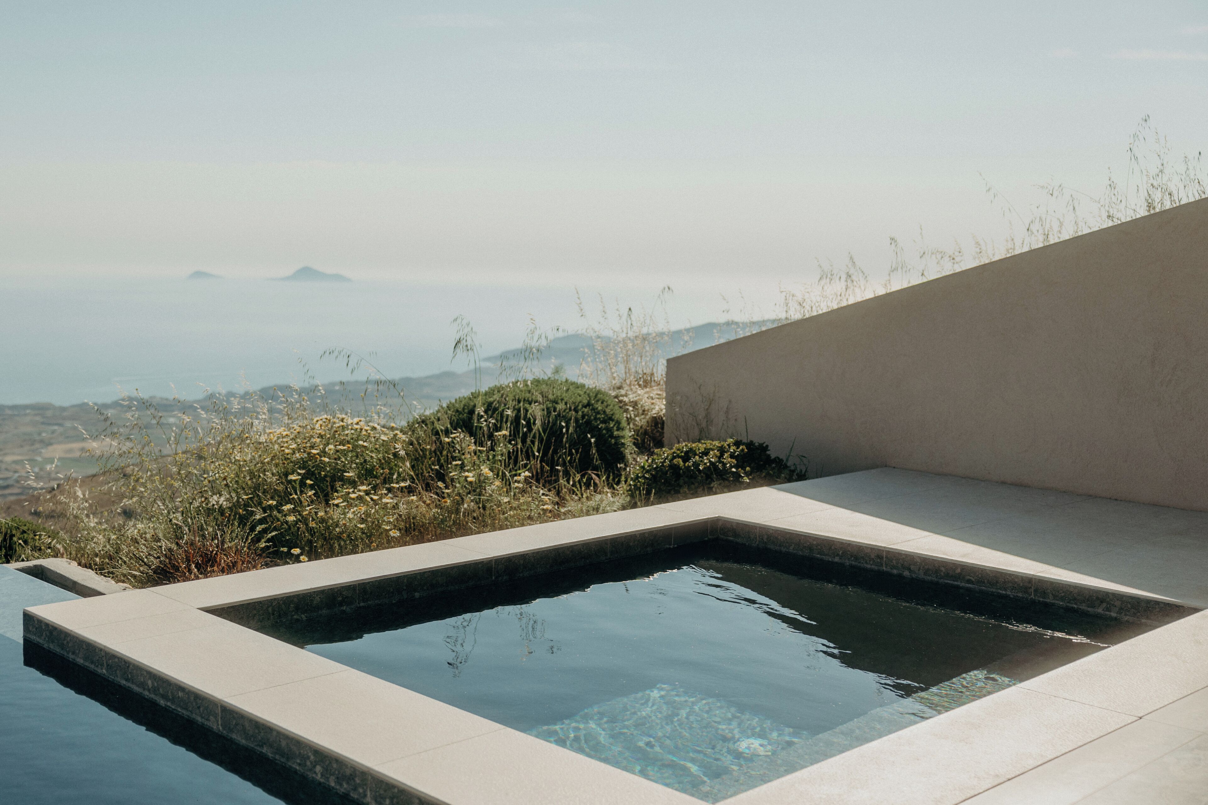 A modern outdoor pool with a clear view of distant hills and mountains.