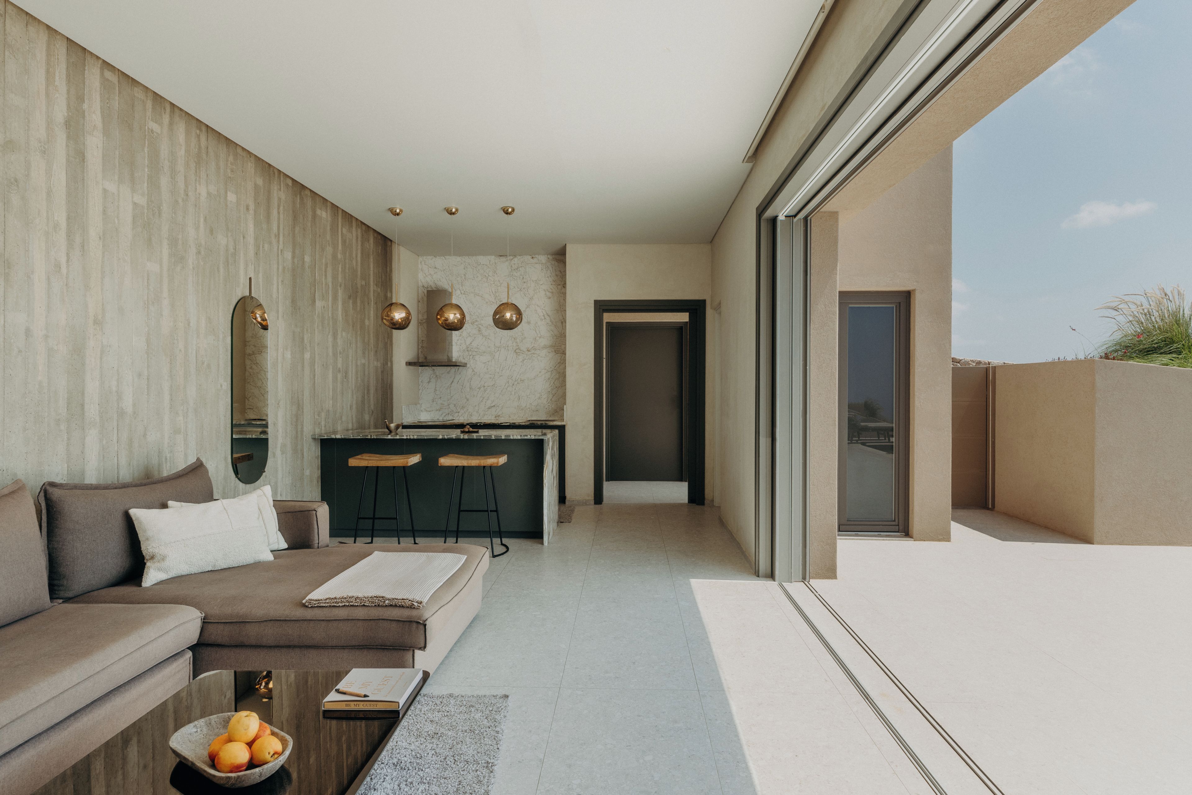 A modern interior with a sofa, a dining area, and a kitchen.