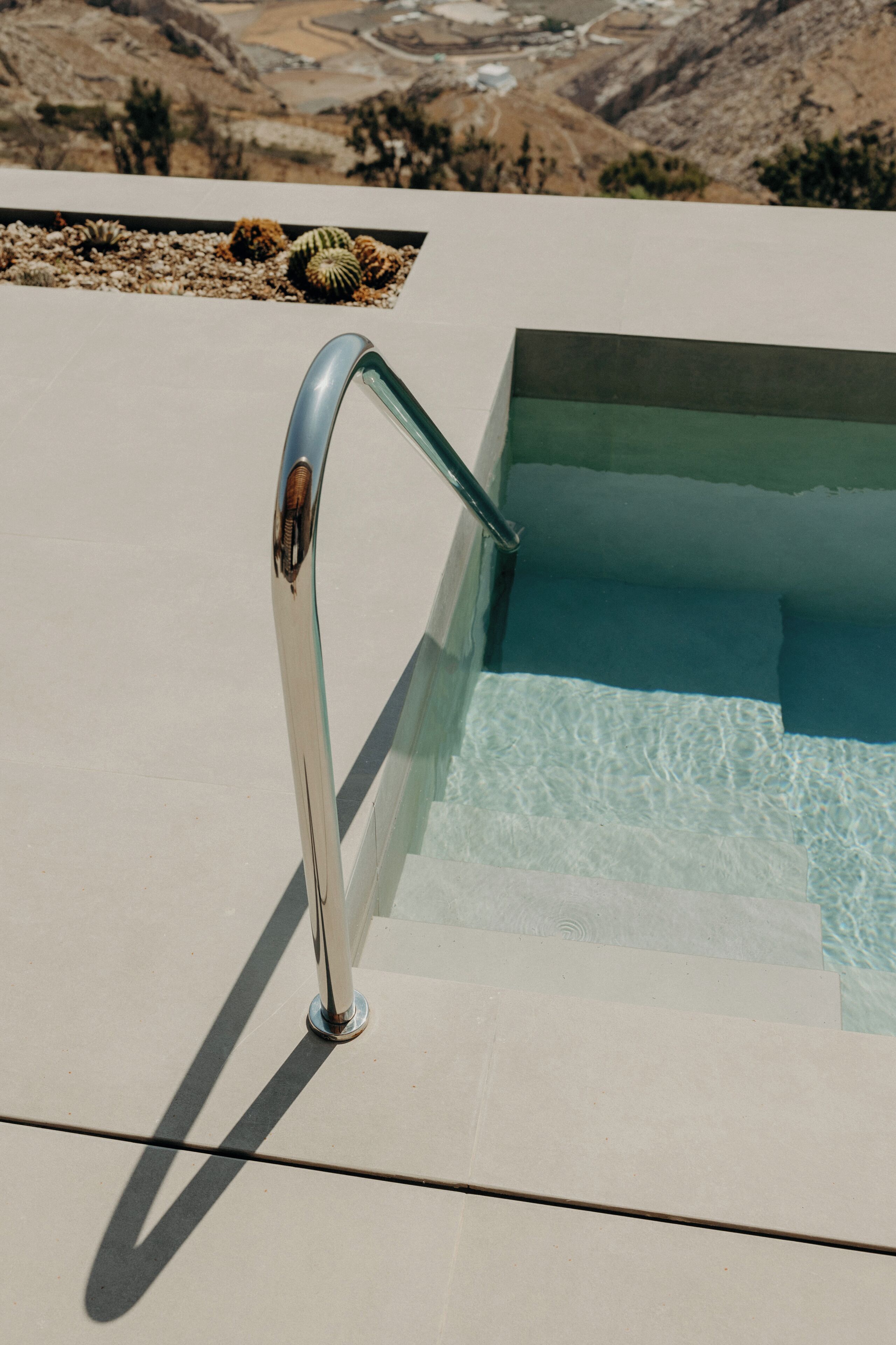 Zona junto a la piscina con barandilla de metal y agua cristalina.