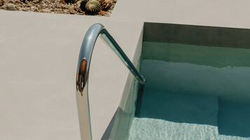 A poolside area with a metal handrail and clear blue water.