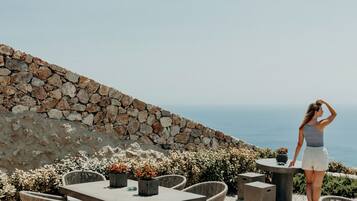An outdoor seating area with stone walls, wicker furniture, and potted plants.