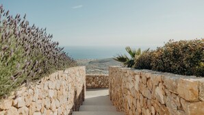 A stone staircase leading to a scenic overlook with lavender and other vegetation on either side. - Santorini Sky, Luxury Resort (Santorini)