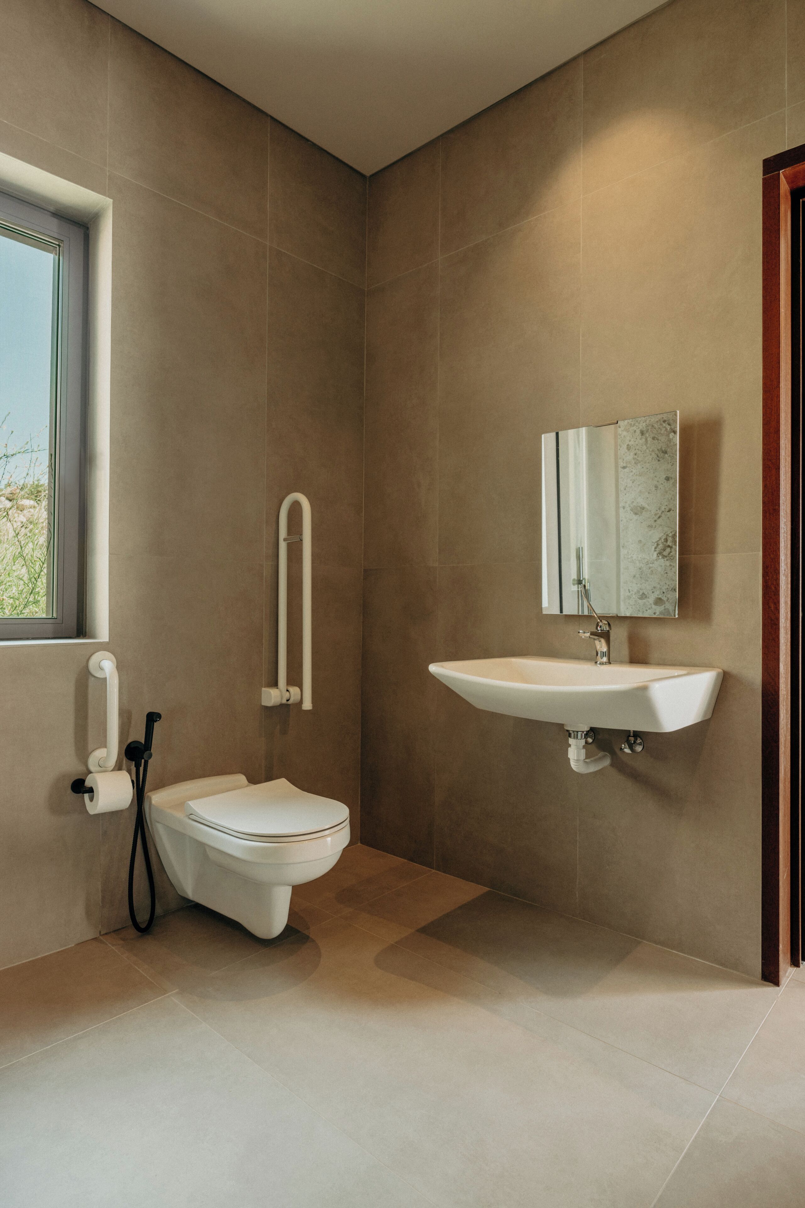 A modern bathroom with a toilet, sink, and mirror.