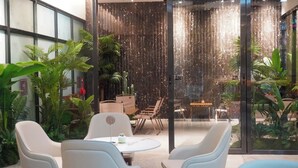 A modern indoor space with a glass wall, a seating area with chairs and a table, and a variety of indoor plants. - Holiday Inn Express Nanning Jiangnan by IHG (Nanning)