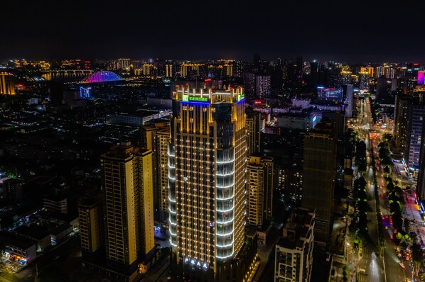 A high-rise building with multiple floors, surrounded by other tall buildings in a cityscape at night. - Holiday Inn Express Nanning Jiangnan by IHG (Nanning)