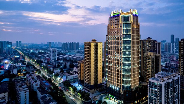 A high-rise building with multiple floors, surrounded by other buildings and a busy street with vehicles. - Holiday Inn Express Nanning Jiangnan by IHG (Nanning)