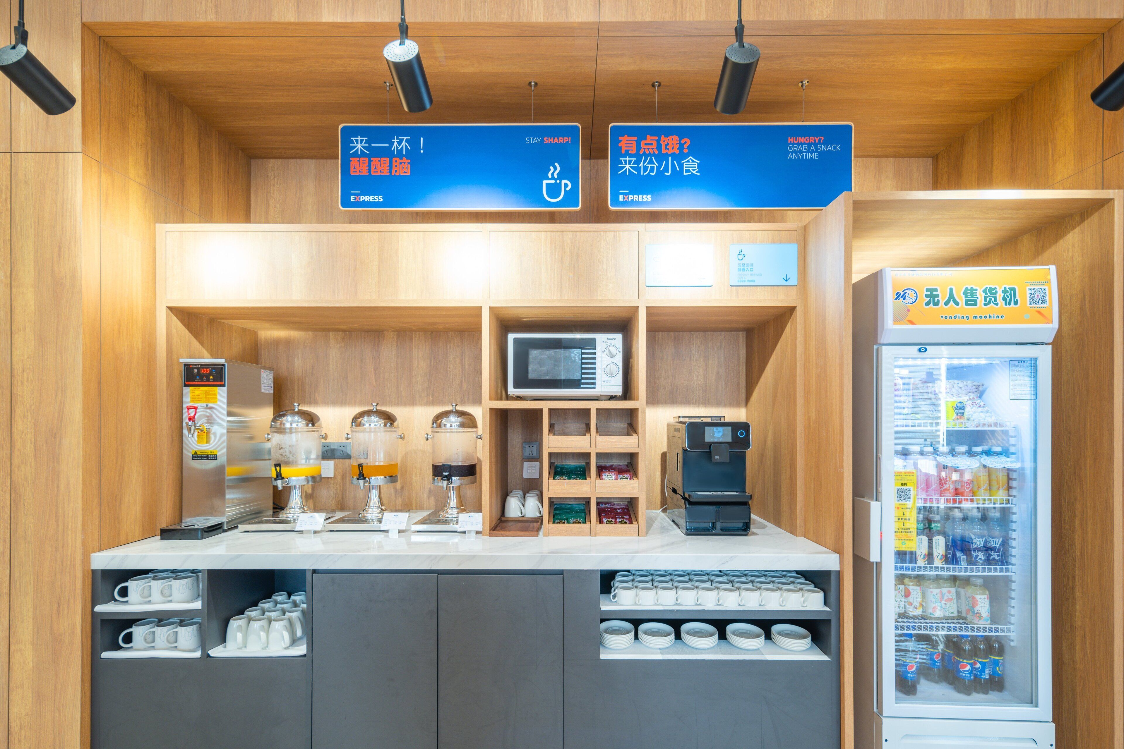 Una estación de café con microondas, máquina de café y dispensadores de bebidas.