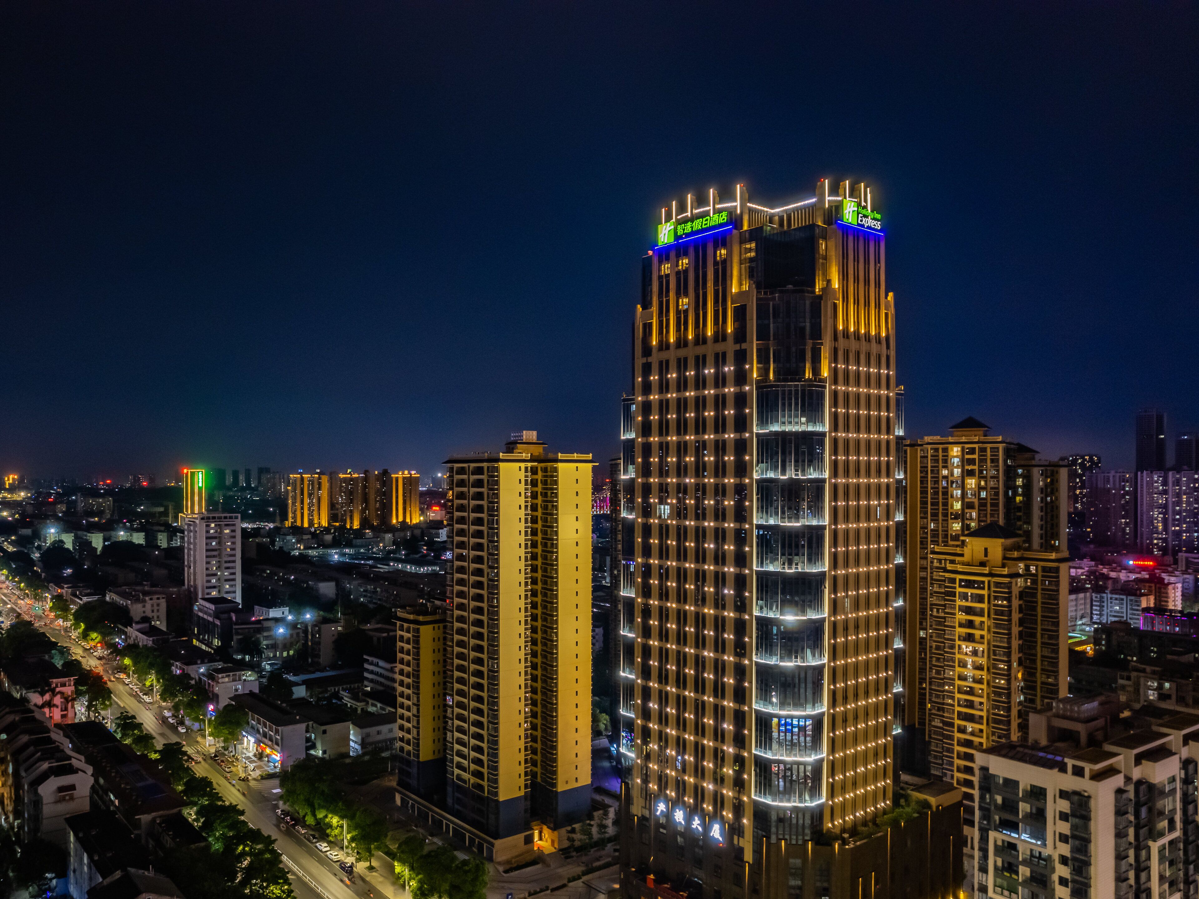 A high-rise hotel with multiple floors, illuminated windows, and a prominent sign at the top.