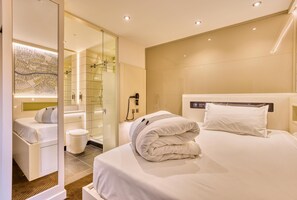 A modern hotel room with a bed, a bedside table, a mirror, a glass shower enclosure, and a map on the wall. - Hub By Premier Inn London Shoreditch (London)