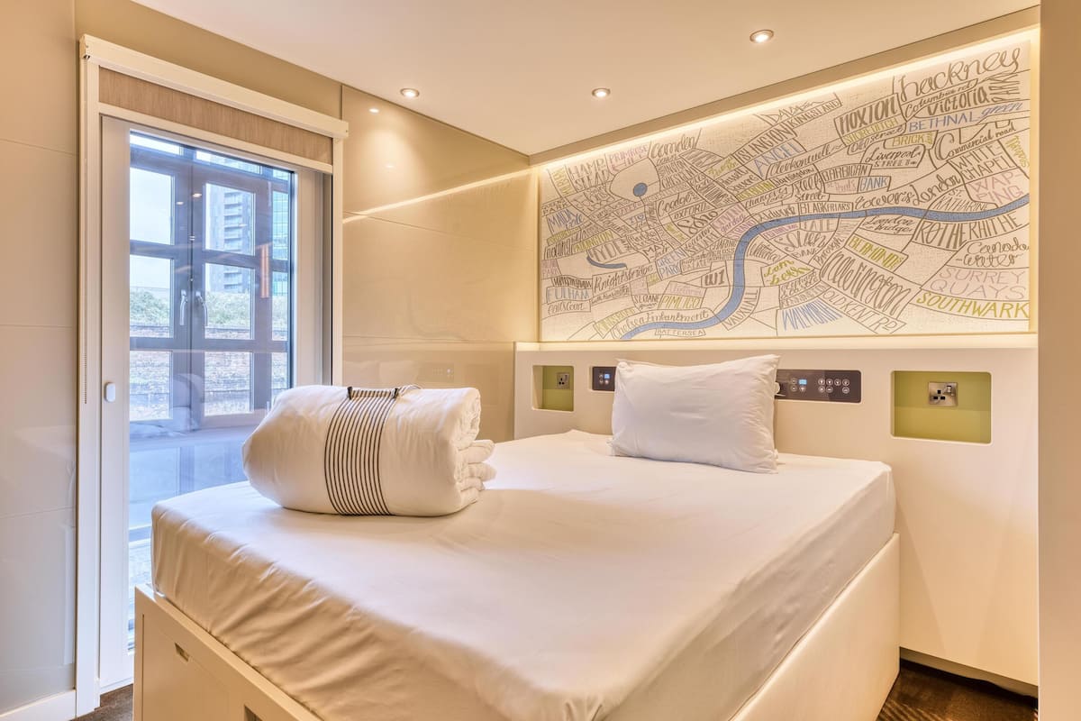 A hotel room with a bed, a map on the wall, and a sliding door to the outside.