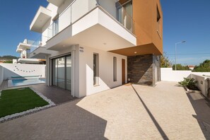 Ein modernes, zweistöckiges Haus mit Swimmingpool, Steinmauer und blauem Himmel.