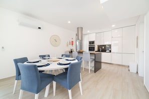 A modern kitchen with white cabinets, a stainless steel range hood, and a built-in oven.