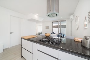 A modern kitchen with a central island, a gas stove, and a stainless steel range hood.