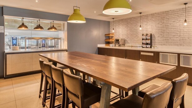 Una cocina moderna con una mesa de comedor de madera, taburetes de bar e iluminación colgante.