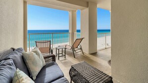 Un balcon avec vue sur l’océan, aménagé avec un canapé, des fauteuils et une petite table.