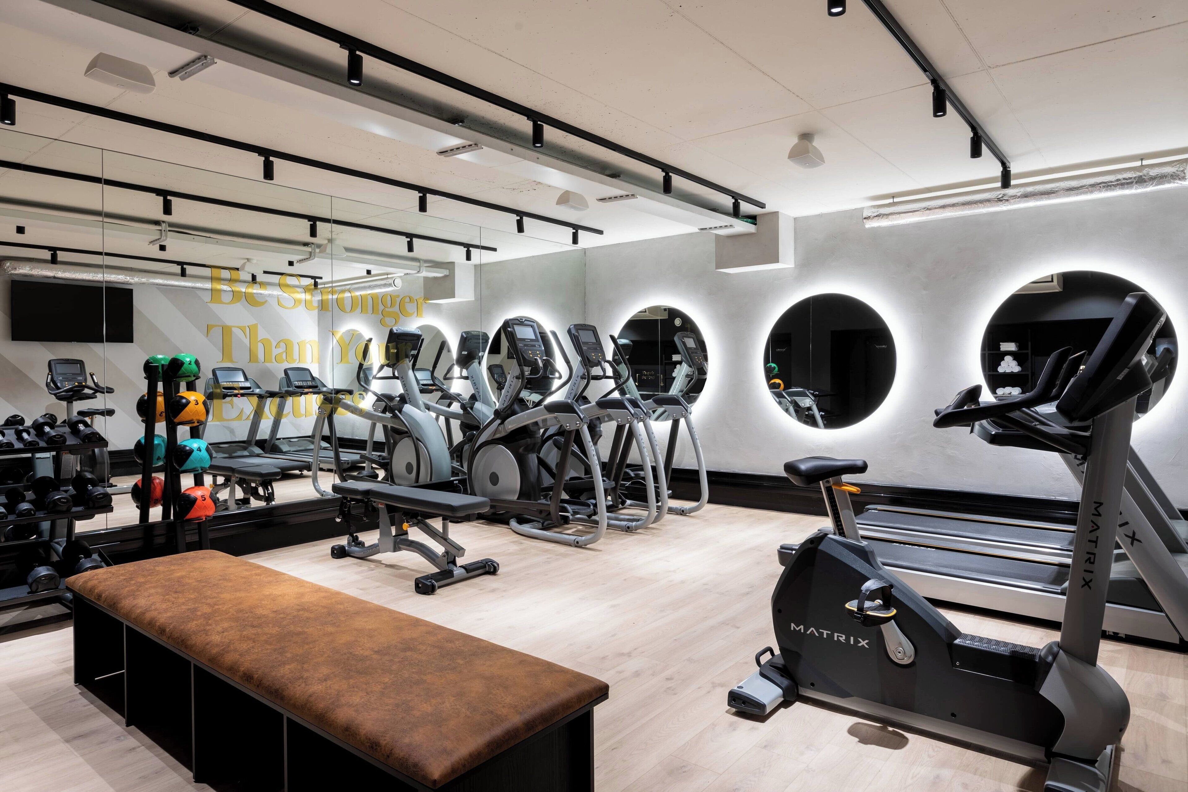 Une salle de sport moderne équipée de divers appareils d’exercice, notamment des tapis de course, des vélos elliptiques et un banc de musculation.