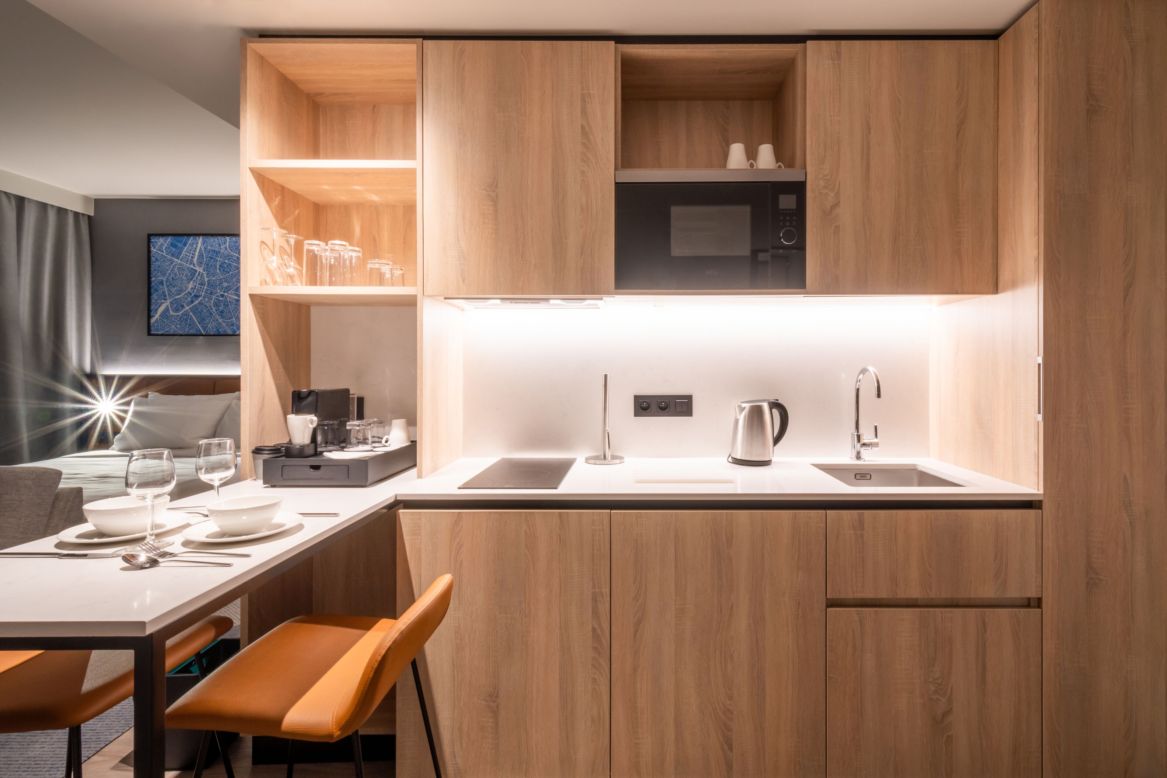 Una cocina moderna con armarios de madera, encimera blanca y microondas integrado.