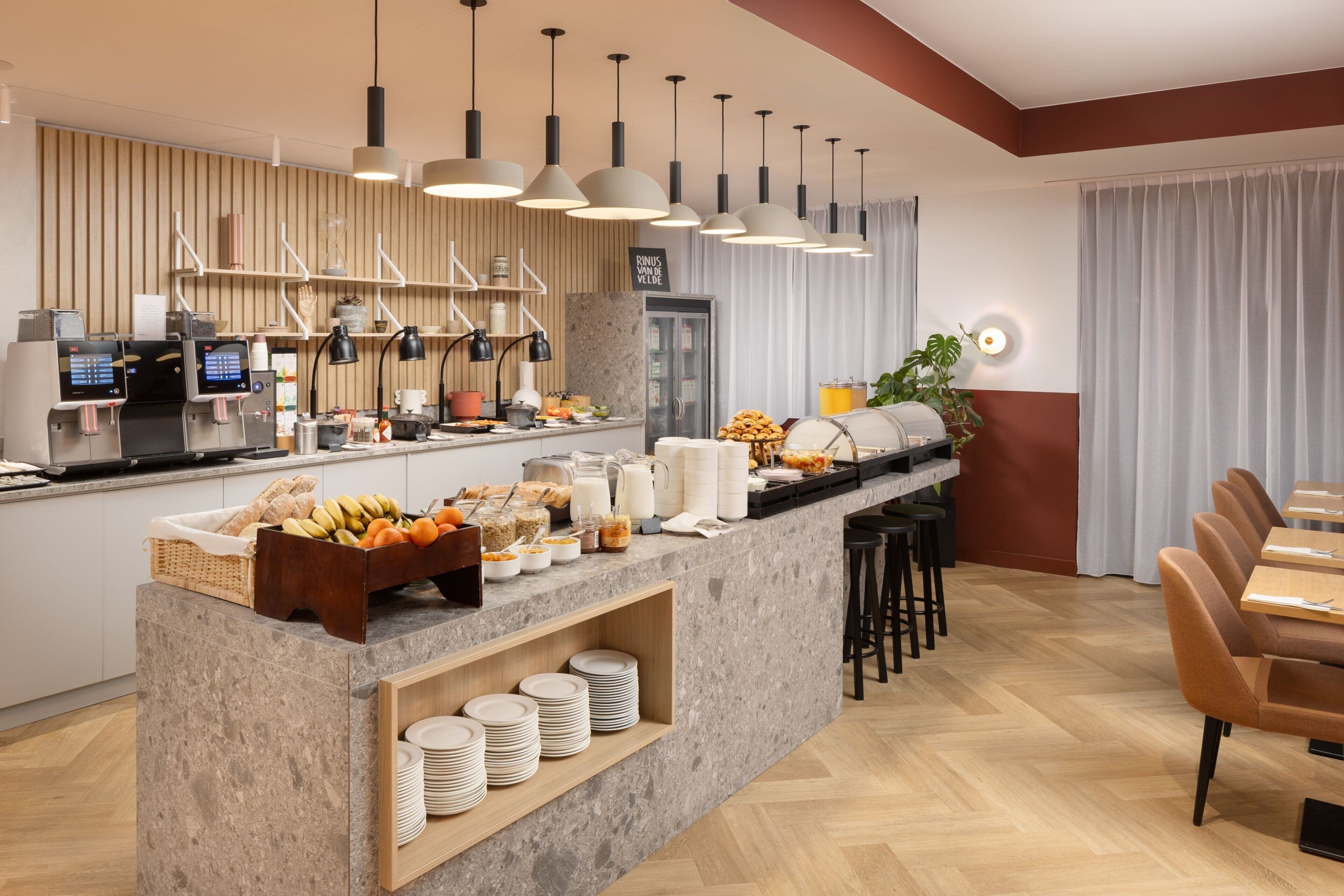 A modern breakfast bar with self-service coffee machines, a variety of breakfast items, and a seating area with tables and chairs.