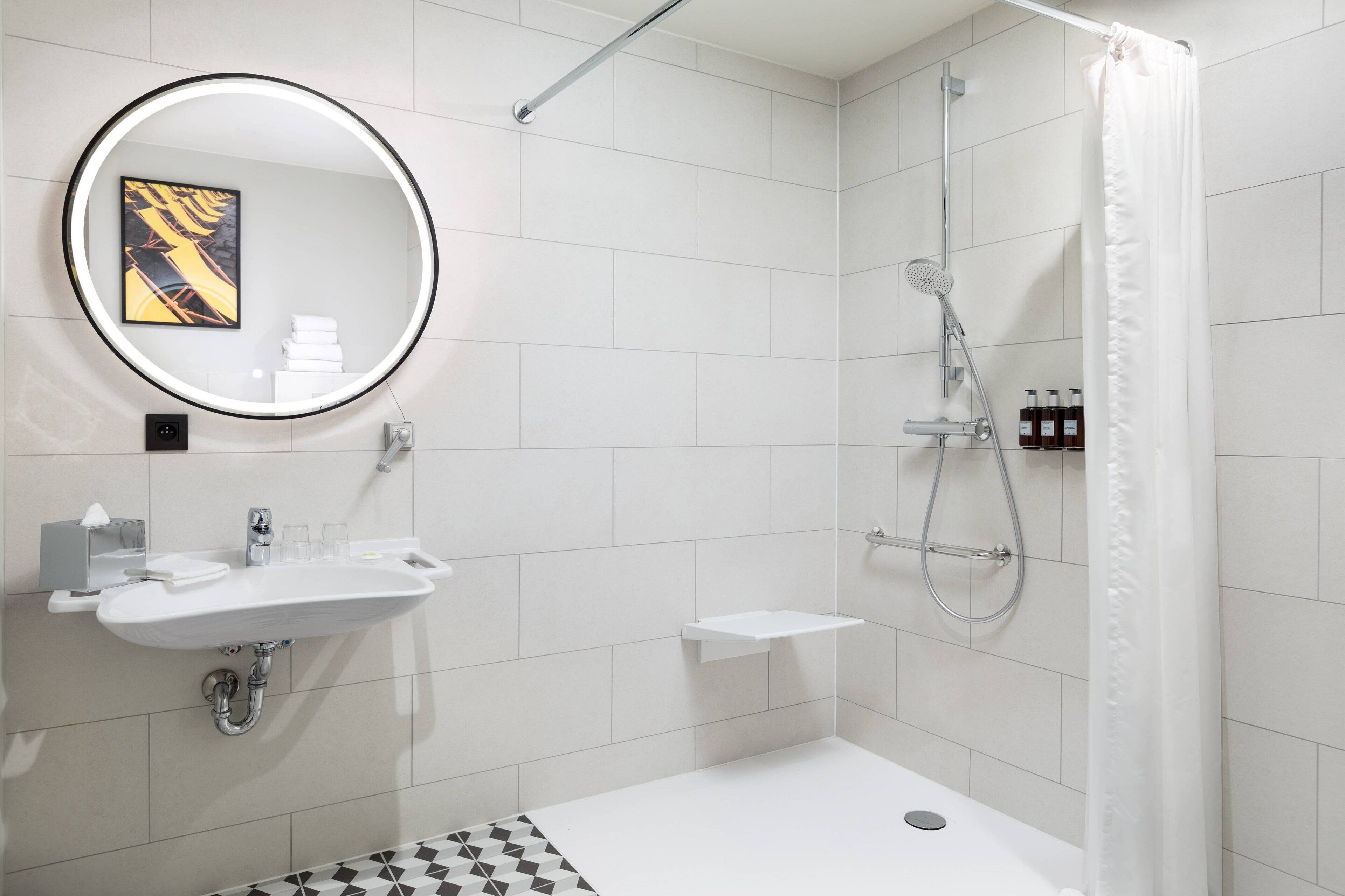 A modern bathroom with a white sink, mirror, and shower.